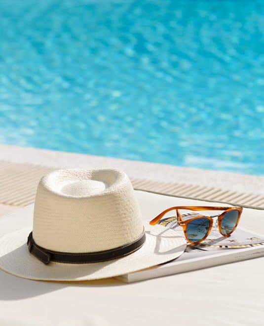 White sun hat next to sunglasses by the swimming pool at Sea Meadow community